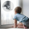 A baby is looking at a window with an adjustable aluminum sliding window lock stopper visible on the frame.