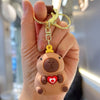 A hand holds an adorable capybara keychain charm with a heart detail.