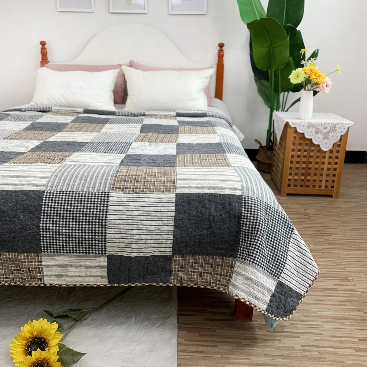 A patchwork cotton bedspread featuring a gray, black, and white checkered pattern on a bed.