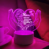 A glowing heart-shaped LED night light illuminates text for a mother with open arms and hugs.