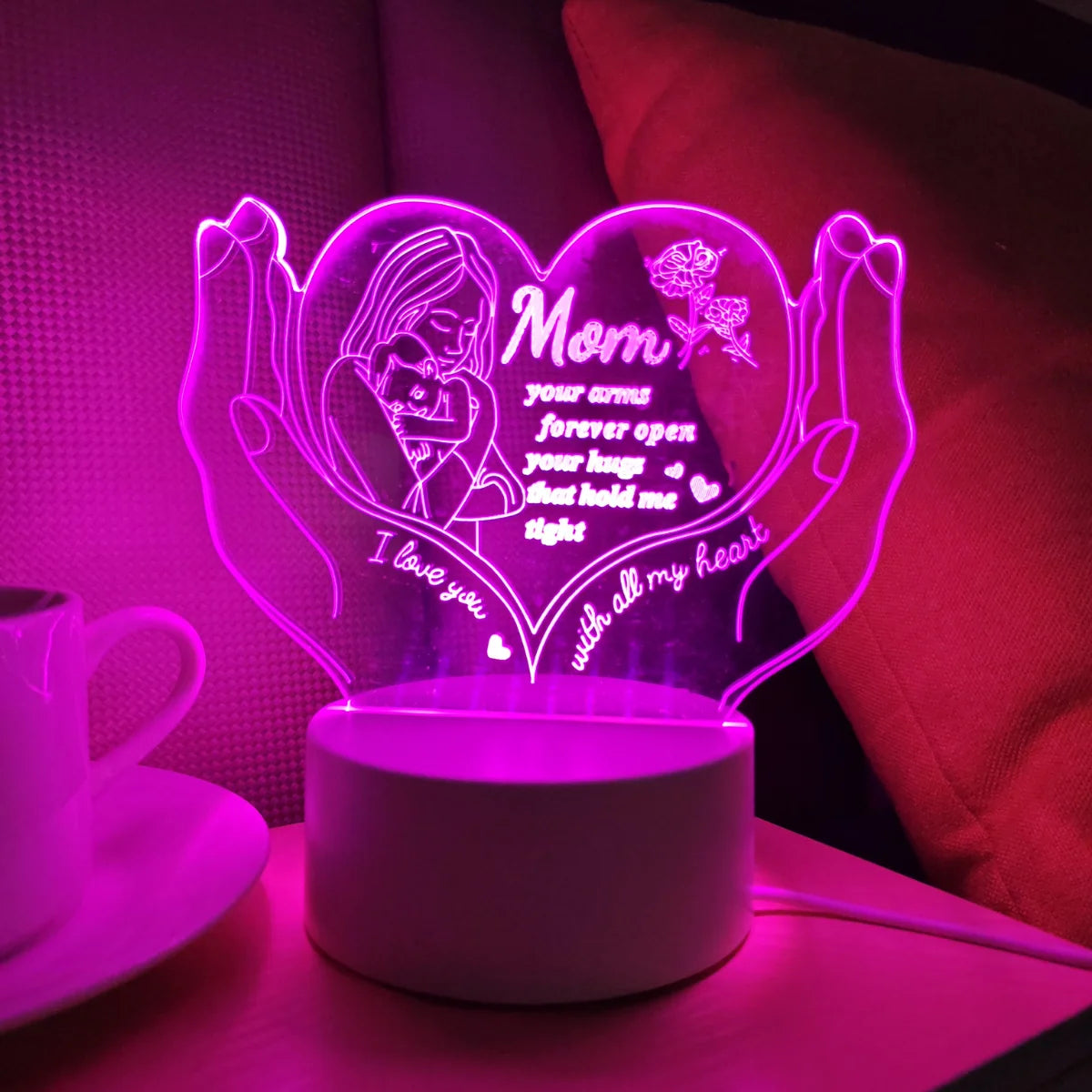 A glowing heart-shaped LED night light illuminates text for a mother with open arms and hugs.