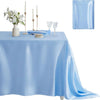 A light blue satin tablecloth set for dining featuring a floral centerpiece, candles, and glassware.