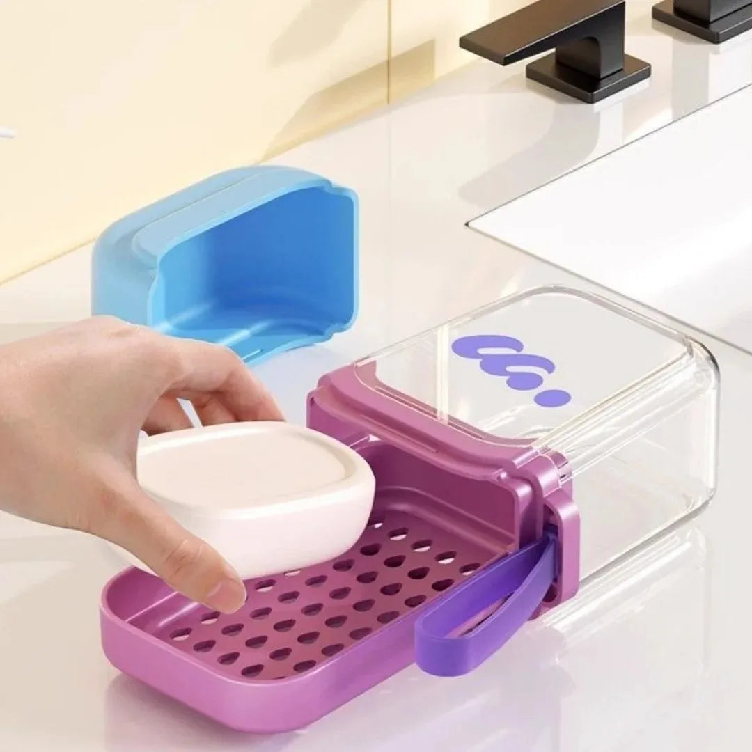 A hand is holding a pink silicone soap case with a secure lid and a clear plastic container on a white surface.