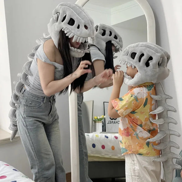 Eine Frau mit Dinosaurierknochen-Kostümzubehör blickt in den Spiegel, während ein Kind daneben steht.