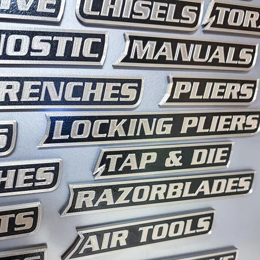 A collection of 12 black and silver magnetic toolbox labels for various tools including chisels, torcs, manuals, wrenches, pl