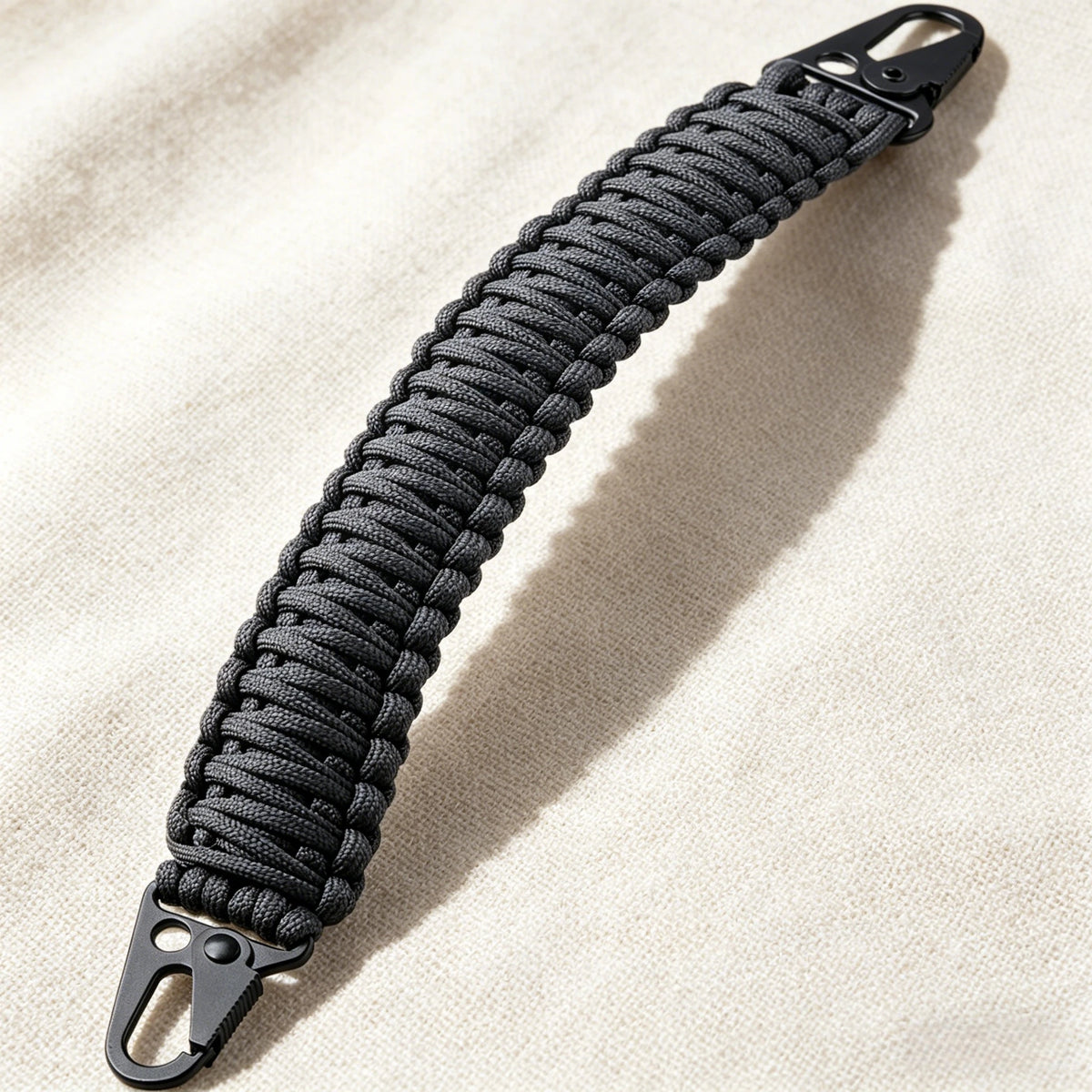 A close-up of a black paracord handle with metal hooks, used for tactical bags and backpacks.