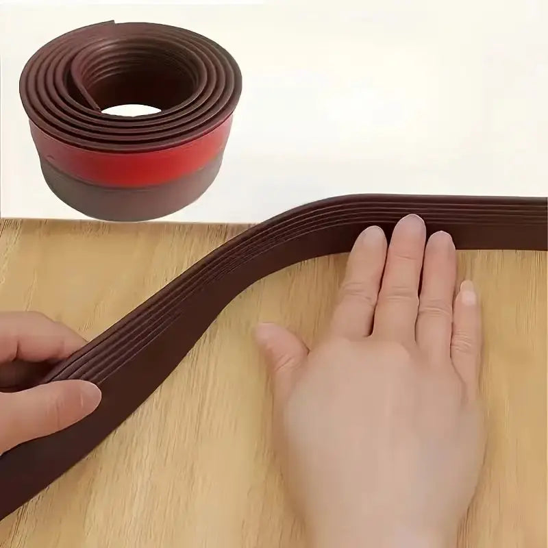 A roll of brown door draft stopper material next to a hand demonstrating the flexible, self-adhesive under-door seal.