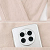 A close-up view of a white smartphone placed inside a light pink cotton kitchen apron.