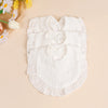 A set of three white soft cotton ruffle bibs laid on a light background with yellow flowers.