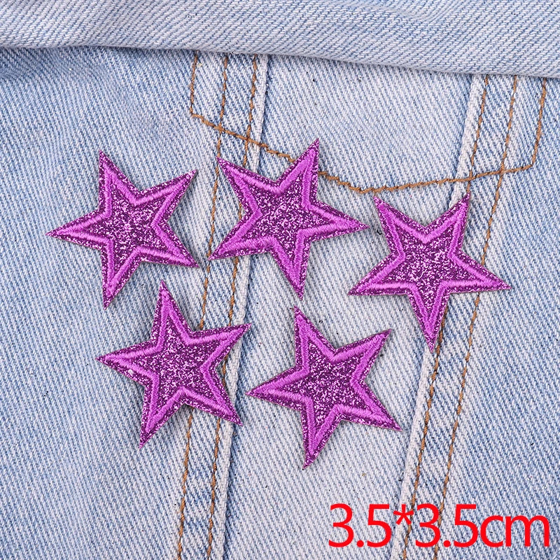 Set of five purple glitter star iron-on embroidered patches on light blue denim fabric