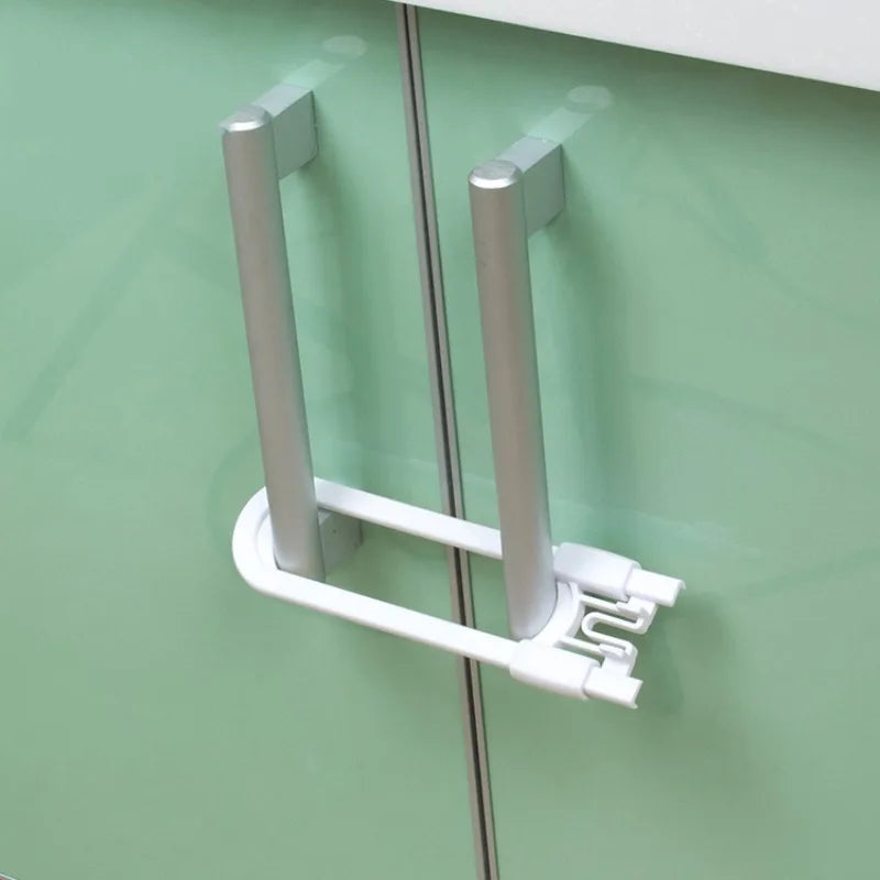 A close-up view of adjustable U-shaped cabinet locks in silver and white mounted on a green cabinet door.