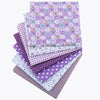 A bundle of purple and white cotton fabric squares featuring various floral dot patterns for patchwork and quilting
