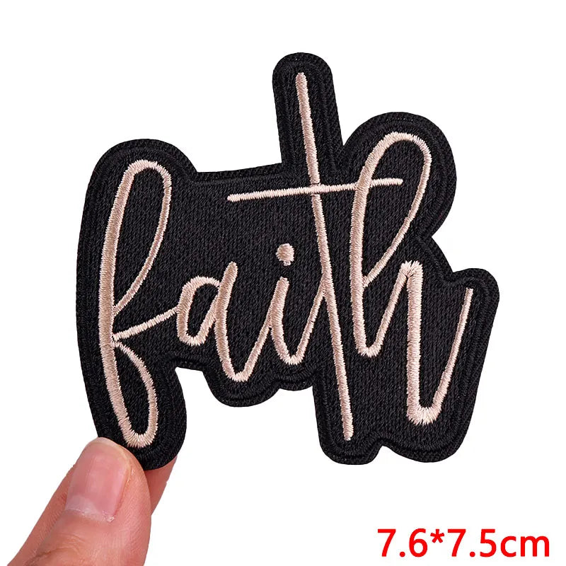 Black embroidered iron-on patch with the word faith in light beige thread