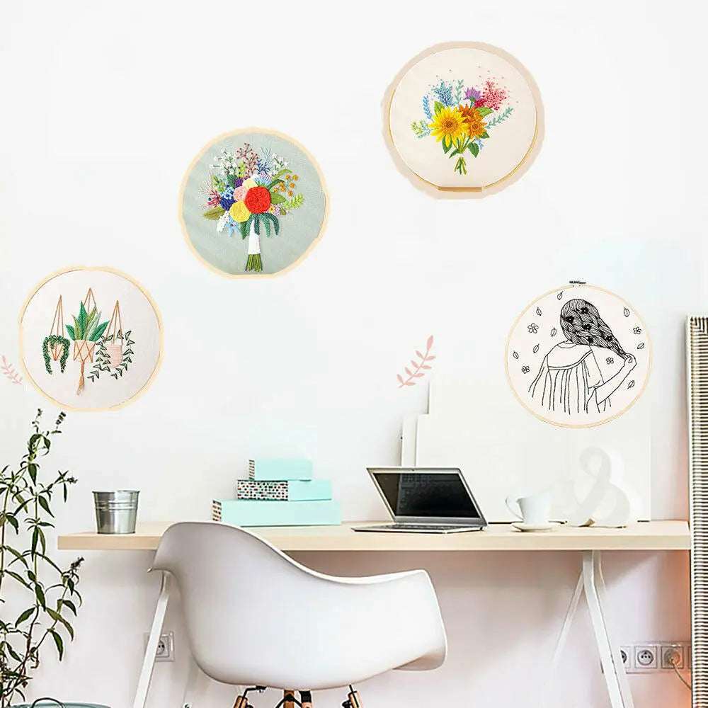 A collection of circular embroidery pieces featuring floral designs on a white wall above a wooden desk.