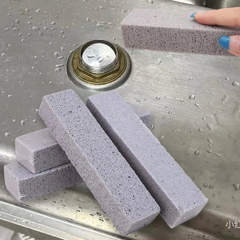 Several gray pumice stone cleaning sticks are displayed on a stainless steel surface next to a metal cap.