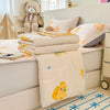 A beige lace-trimmed breathable summer duvet is displayed on a bed with stuffed animals and a blue patterned rug.