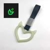 A light green heart-shaped car handle decor with a holographic finish is shown next to its packaging.