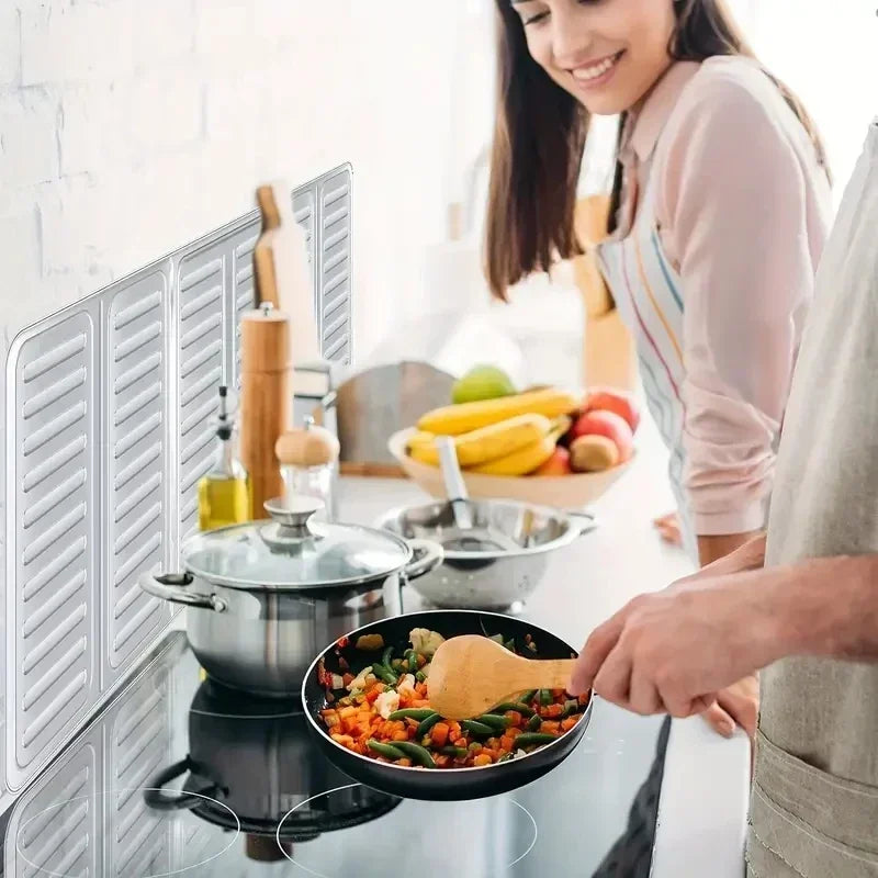 A person is cooking in a pan on a stovetop, with a foldable aluminum stove splatter guard visible.