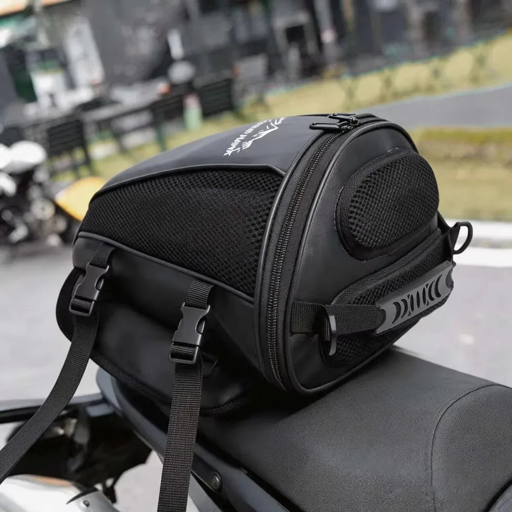 Black waterproof motorcycle tail bag with a mesh pocket and strap attached to a motorcycle seat.