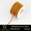 A spool of multi-color glass rhinestone cup chain with a gold-yellow hue and a long dangling strand.