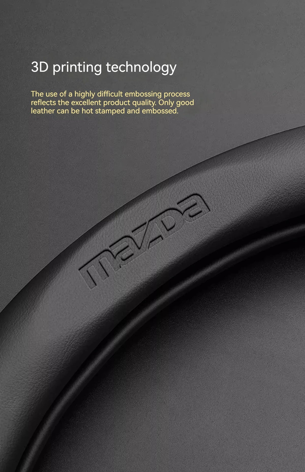 Close-up of a black leather steering wheel cover with the Mazda logo embossed on it.