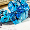 A close-up of a set of bright blue resin dice with black markings, resting on a white surface.