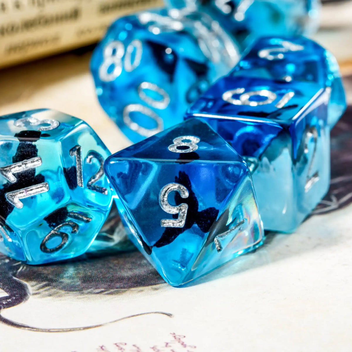 A close-up of a set of bright blue resin dice with black markings, resting on a white surface.
