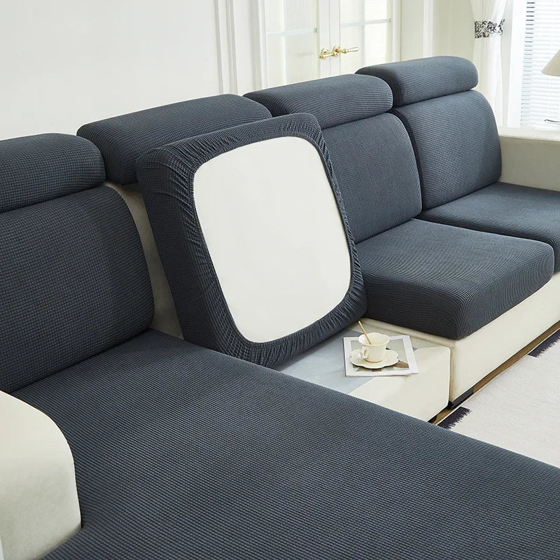 A modern gray Jacquard stretch sofa slipcover with a white accent cushion and non-slip grip.
