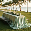 An elegant long satin tablecloth set up outdoors for a wedding or party event.