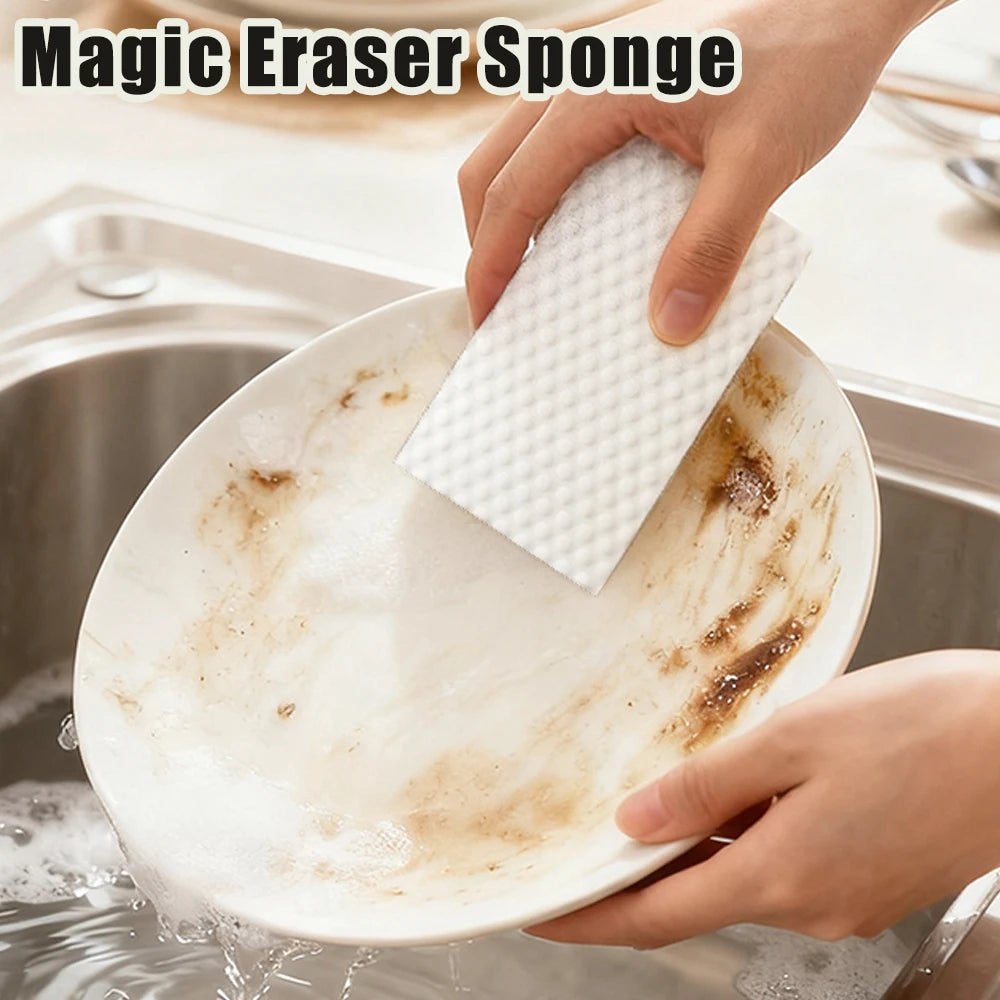 A hand is using a white Magic Eraser sponge to clean a plate in a sink.