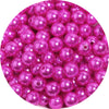 A pile of round, pink imitation pearl beads for jewelry making.