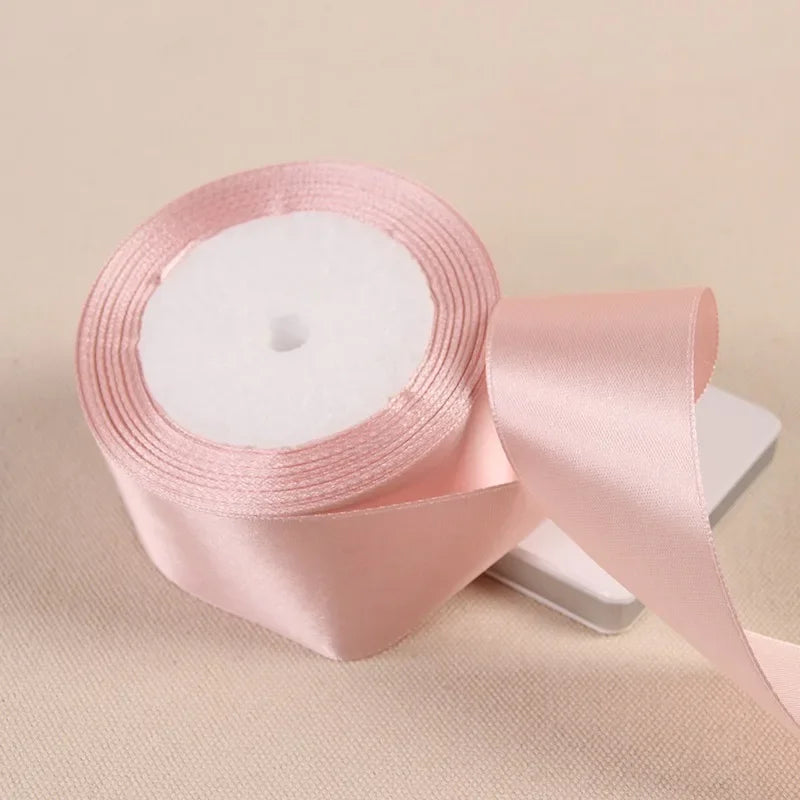 A roll of pink satin ribbon used for gift wrapping and DIY crafts.