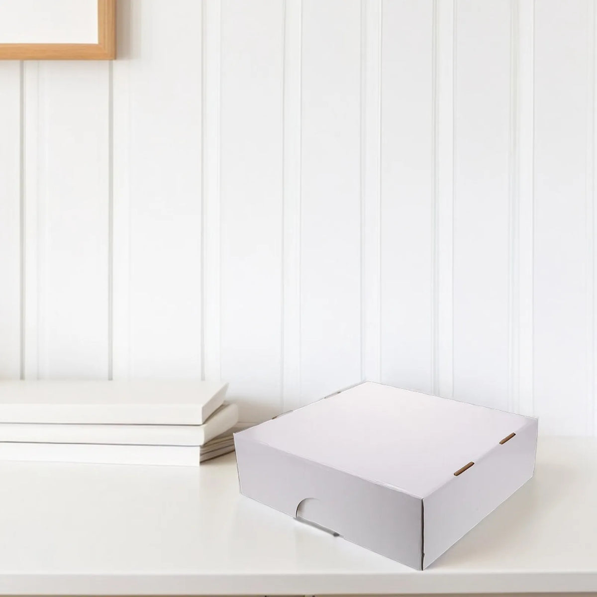 A white, rectangular storage box for trading cards is placed on a white surface next to some stacked white cards.