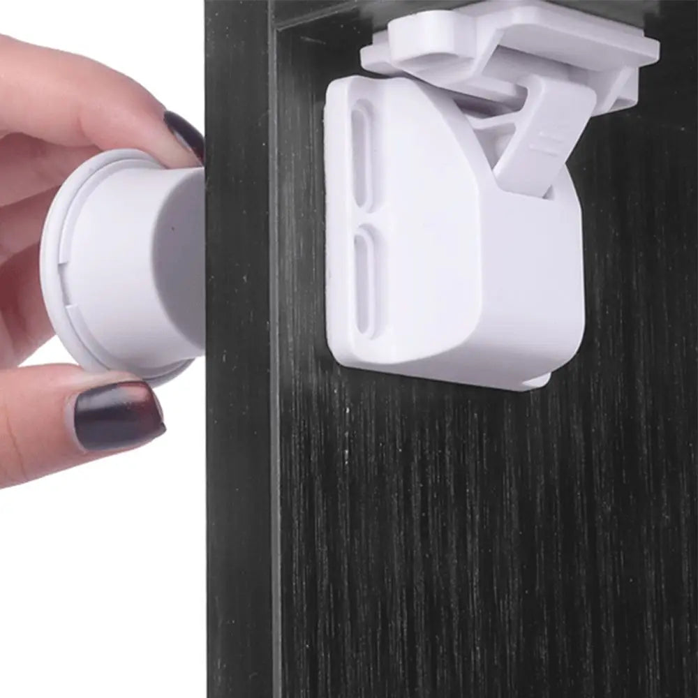 A hand is shown inserting a white magnetic cabinet lock into a dark cabinet drawer.