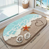 A beige anti-slip bathroom rug with a blue wave design and a heart and starfish decoration.