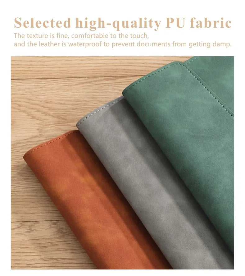 Une pile de trois organisateurs de documents en PU marron, gris et vert, posés sur une surface en bois.