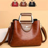 A brown leather vintage crossbody tote bag with a silver hardware detail and multiple pockets shown against a light backgroun