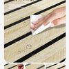 Close-up of a hand wiping water stains off wood grain wallpaper with a white cloth.