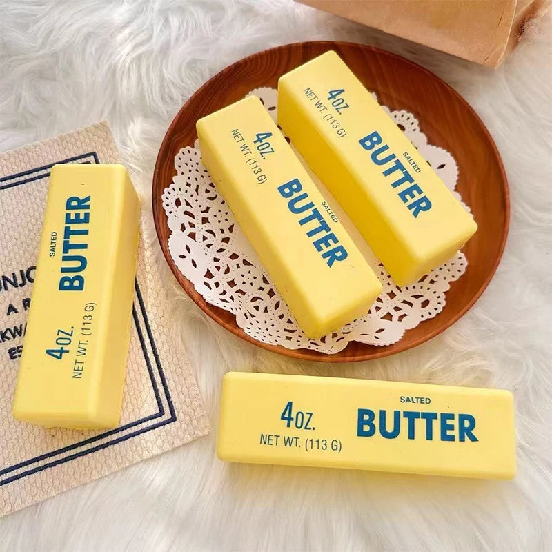 Yellow butter fidget sticks are displayed on a wooden plate with lace, next to another stick.