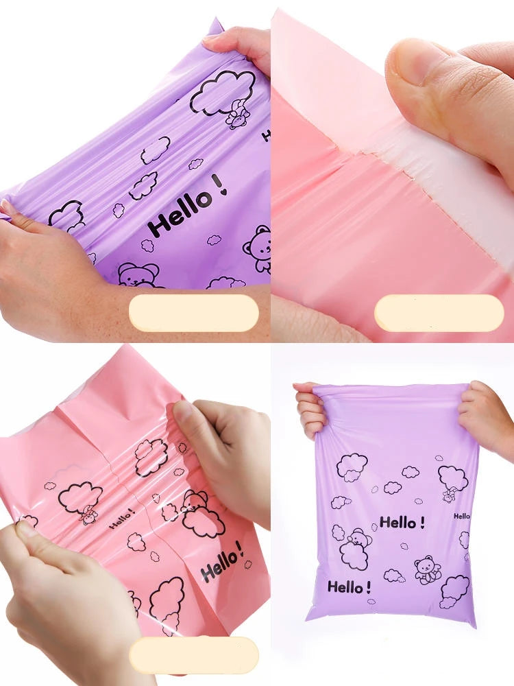 Close-up of purple self-sealing mailing bags featuring a white cloud and hello bear design being held by hands.