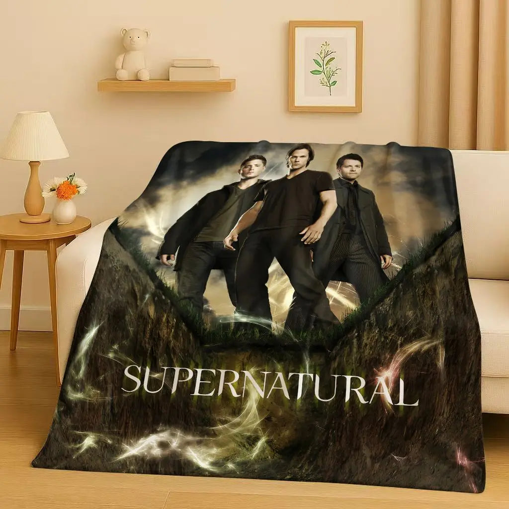 A dark themed blanket featuring three men in dark clothing against a misty background with the word Supernatural printed on i