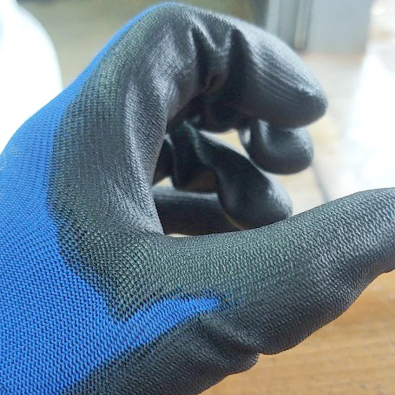 A hand wearing black and blue breathable PU-coated work gloves, showing the grip texture.