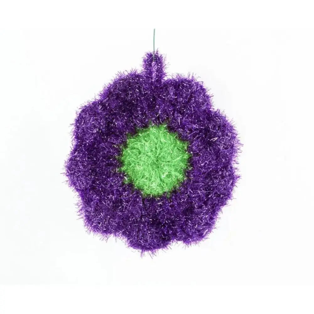 A spherical cleaning sponge made of purple and green acrylic fibers.