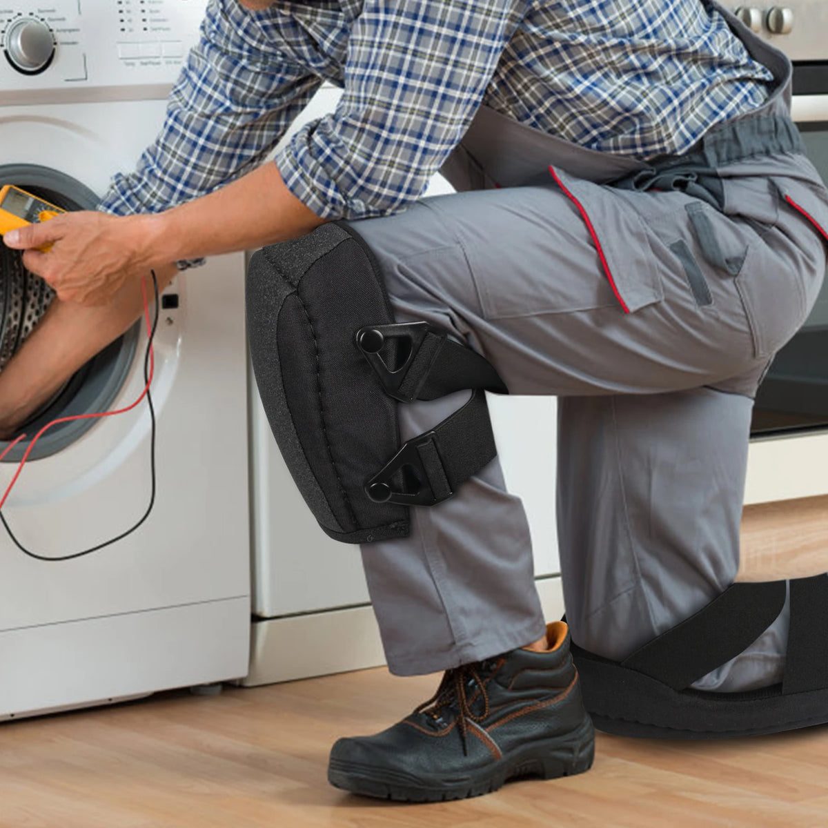 A person wearing plaid shirt and gray pants is putting on black non-slip work knee pads with thick foam padding.