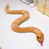 A lifelike, soft, realistic orange and white snake plush toy is coiled on a white surface.