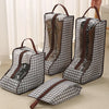 A set of waterproof boot storage bags with handles in a gray and black checkered pattern are displayed on a floor.