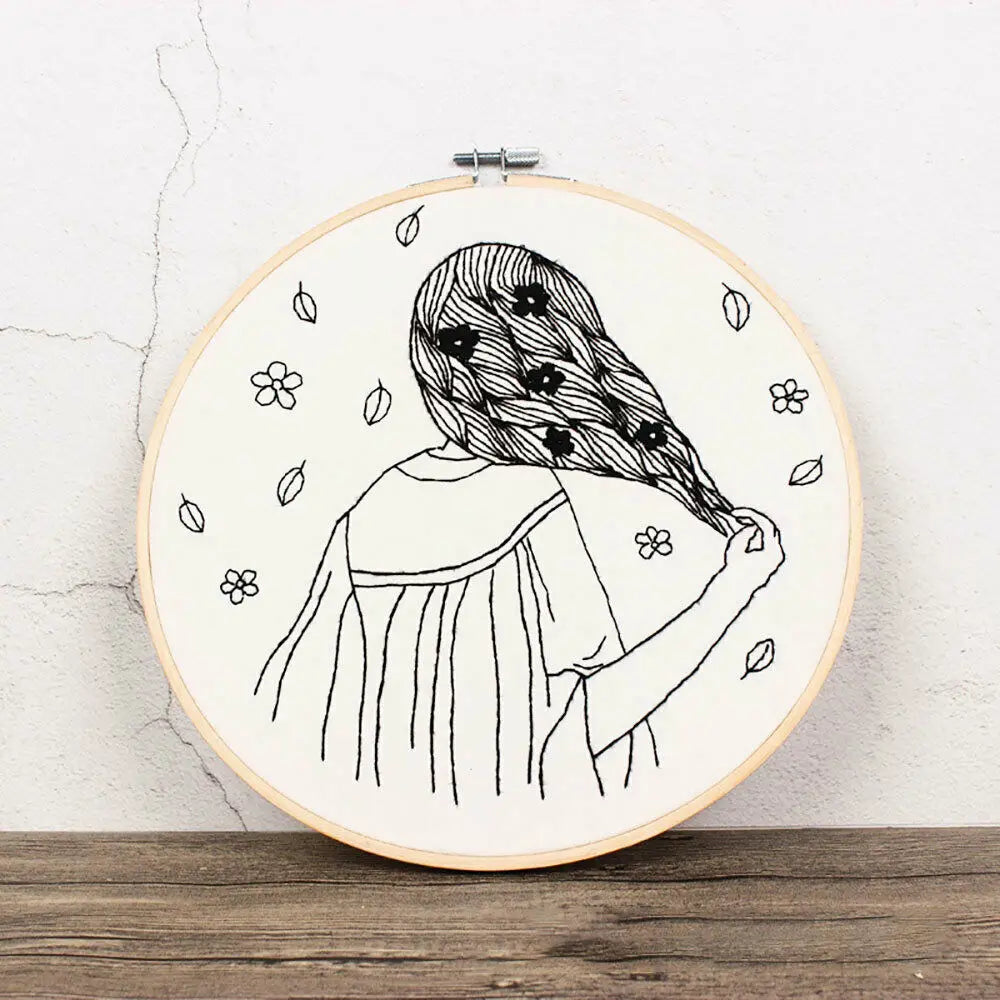 A black line drawing of a woman with long, wavy hair and flowers on her head, ready for floral cross stitch embroidery.