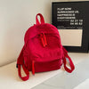 A bright red Japanese corduroy casual backpack resting on a white surface.