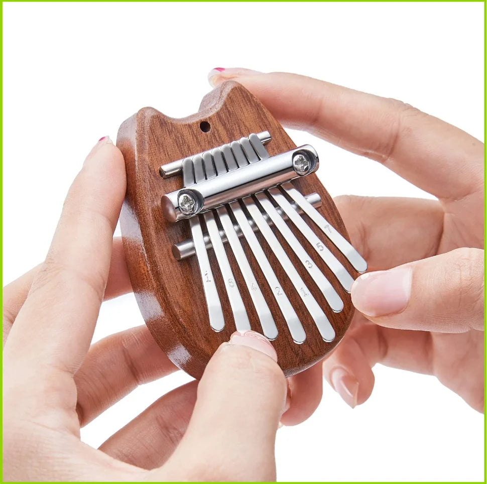 A hand holds a wooden kalimba thumb piano with metal tines, showing the instrument's design.