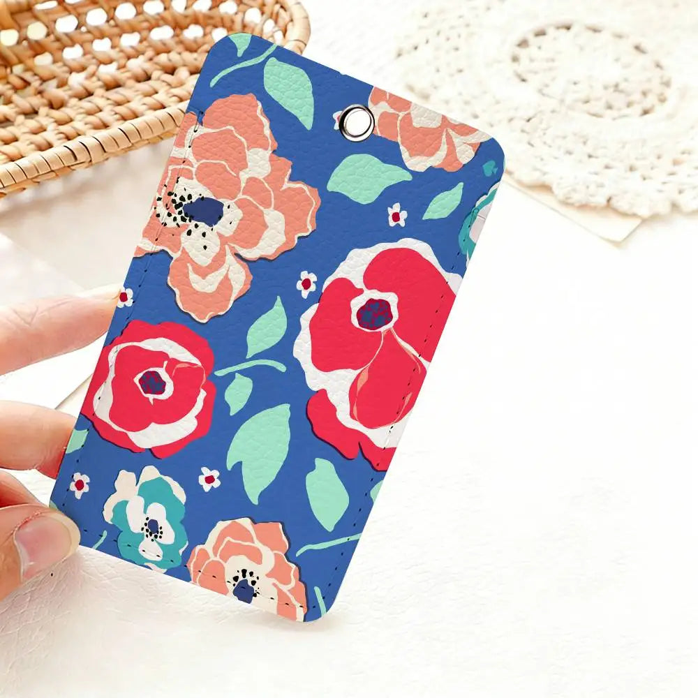 A hand holds a blue floral card holder keychain featuring pink and red flowers on a white background.